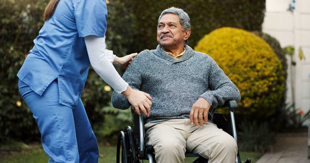 Older adult and family member review Medicare papers at a table beside a medication organizer and walker.